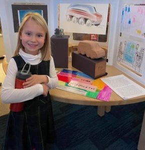 A kindergartener from University Liggett School displaying her creation at the school's Car Show.