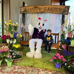 The Easter Bunny sits on a rough hewn bench with a young boy.