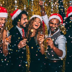 Several adults in Santa hats raising champagne glasses in a toast.