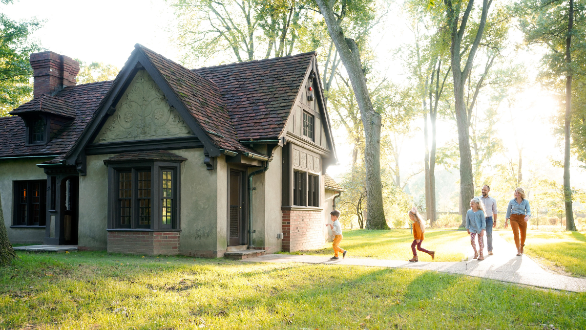 A family with three young children walks beside Josephine’s Playhouse at Ford House during golden hour in autumn.
