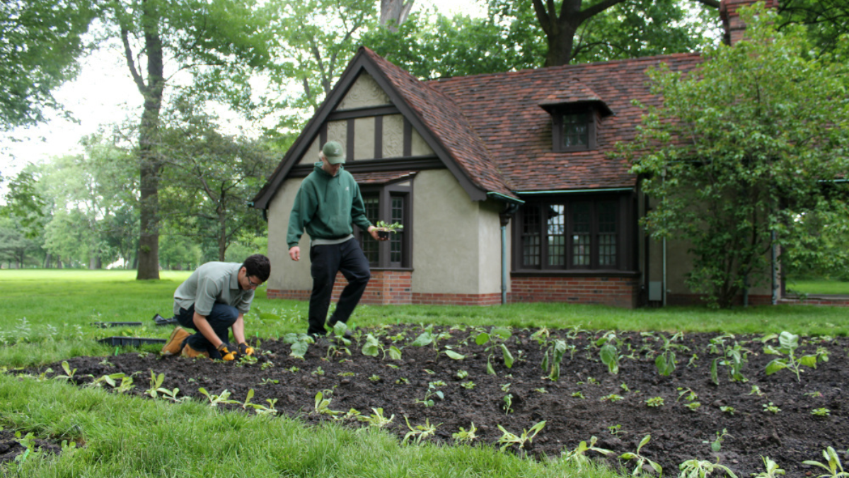 Two staff members plant seedlings in the vegetable garden beside Josephine’s Playhouse, preserving its historical connection to learning and care.