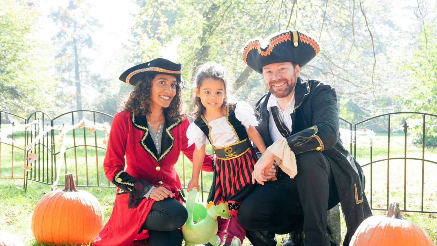 A family dressed as pirates kneels among pumpkins at Ford House, smiling in costume during the Little Goblins event.